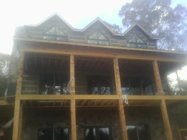 Dormers and porch framing on a large log home under construction — Roof Coating work by our crew in Riverton